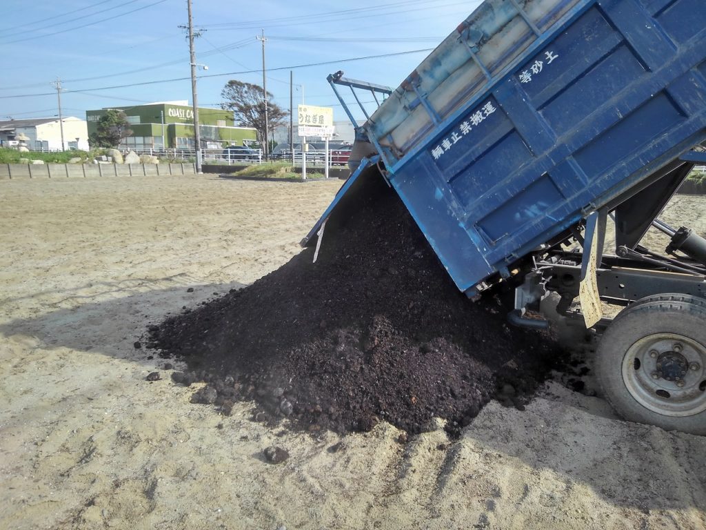 ダンプで運んだ堆肥を畑に降ろす作業